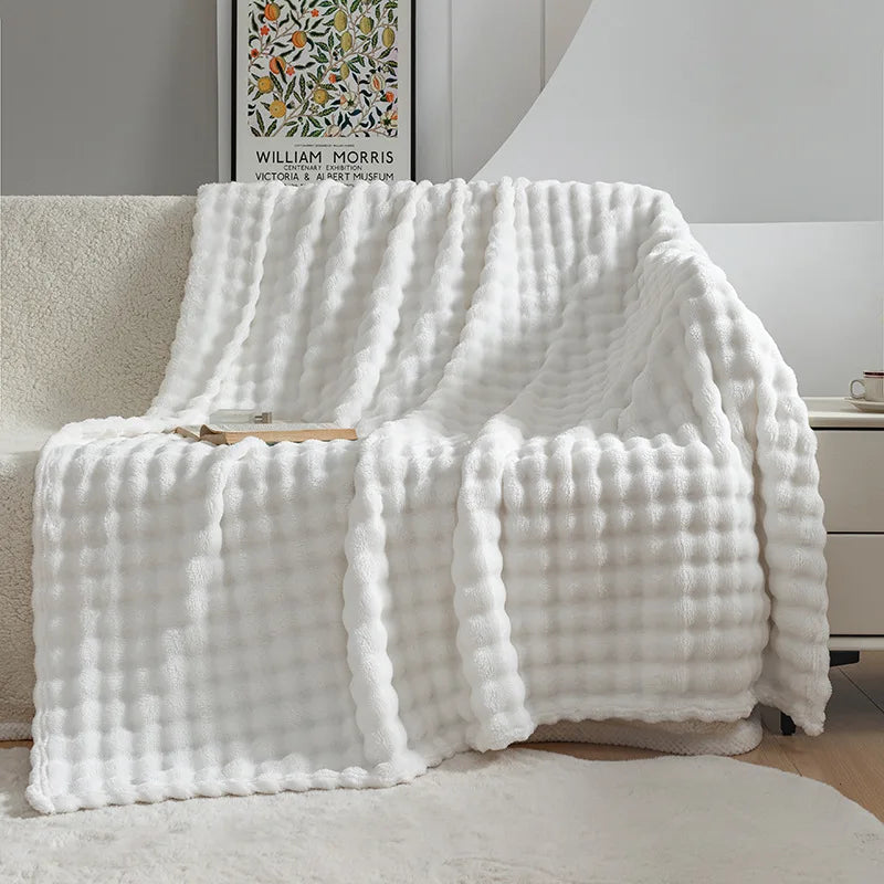 Cozy fleece throw blanket draped over a sofa, adding warm comfort & stylish home decor to living spaces.
