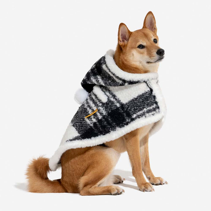Playful dog modeling the cozy red plaid poncho, durable and stylish pet clothing.