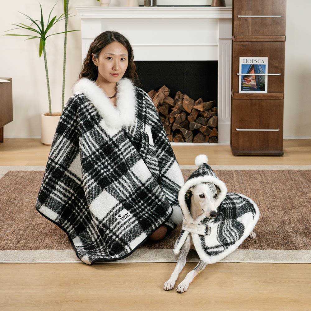 Matching plaid ponchos on a walk, owner and dog in festive winter apparel, cozy pet accessories.