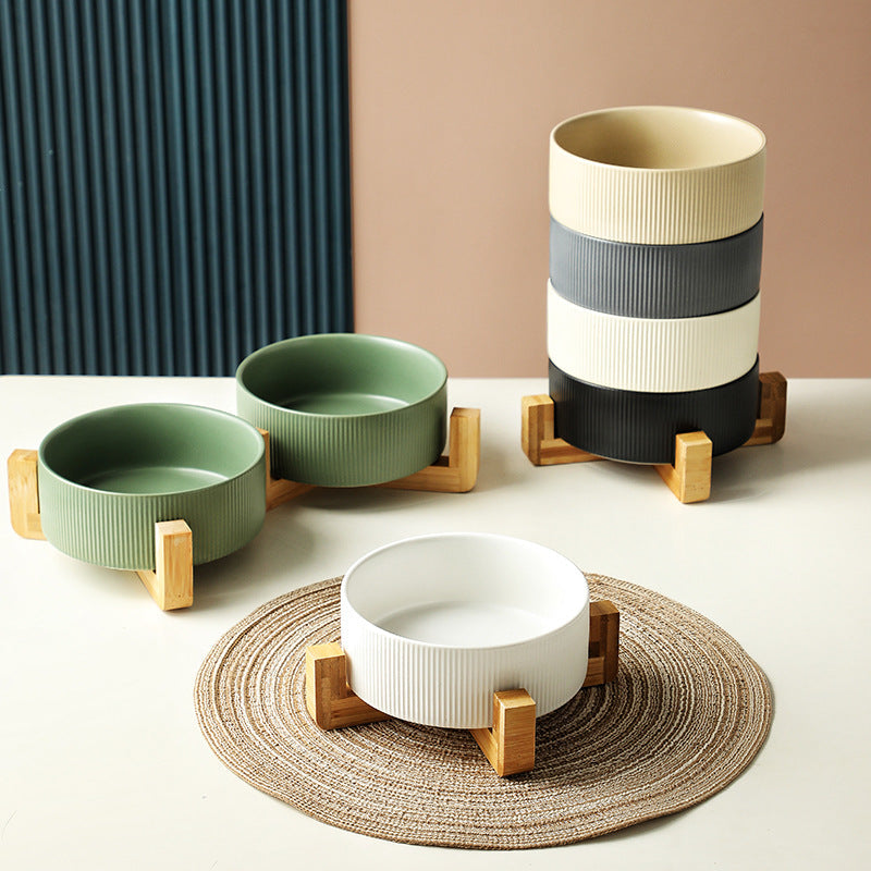 Close-up of a matt green ceramic pet bowl in a wooden stand, dishwasher safe for easy cleaning.