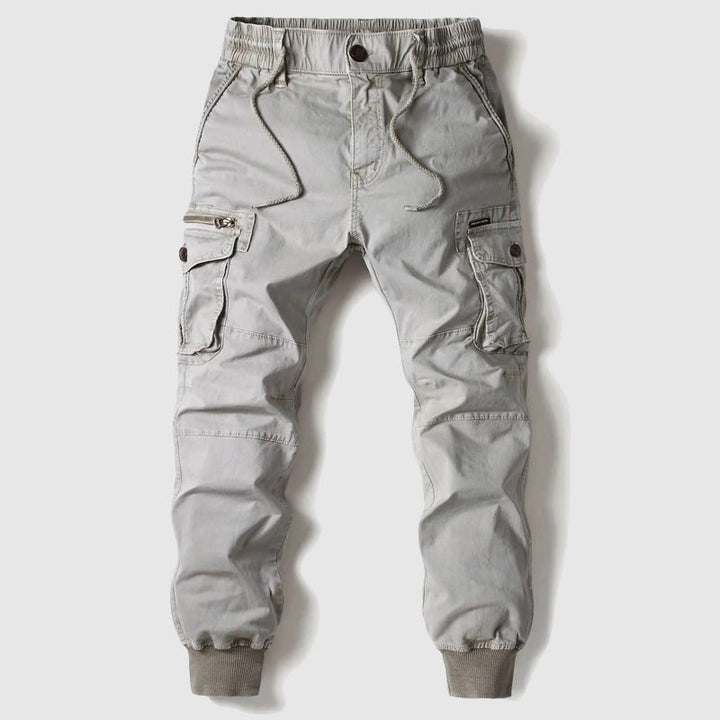 Grey tactical cargo pants for men, versatile design with adjustable waist & ample storage for daily activities.