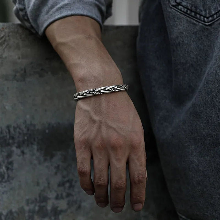 Men's sterling silver braided open cuff bracelet worn on a wrist, showcasing its adjustable & modern design.