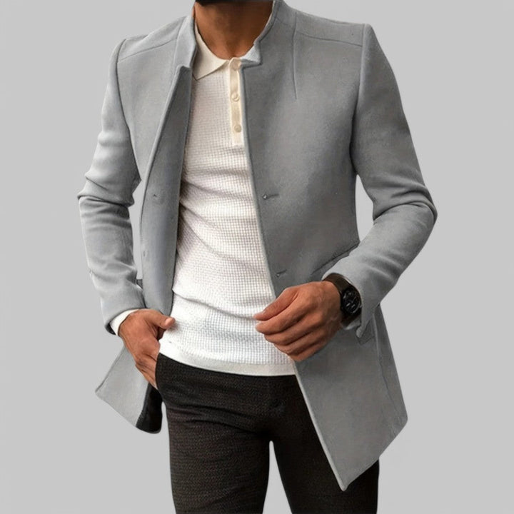 Man wearing a minimalist button winter coat, styled for smart casual. Tailored long sleeve outerwear.
