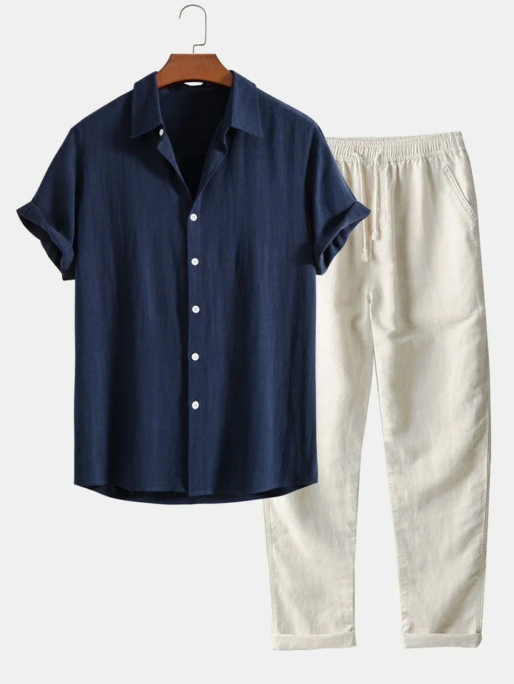 Men's navy blue casual short sleeve button-down shirt and coffee brown relaxed fit pants vacation outfit set.