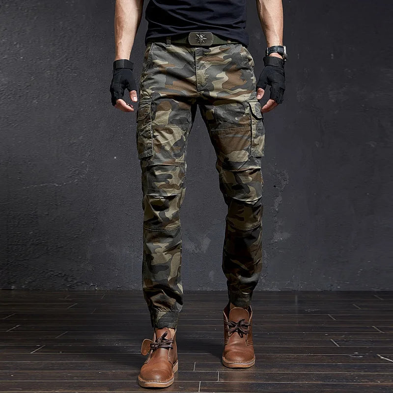 Front view of dark grey Outland men's tactical cargo pants, tapered, multiple pockets, cuffed ankle.