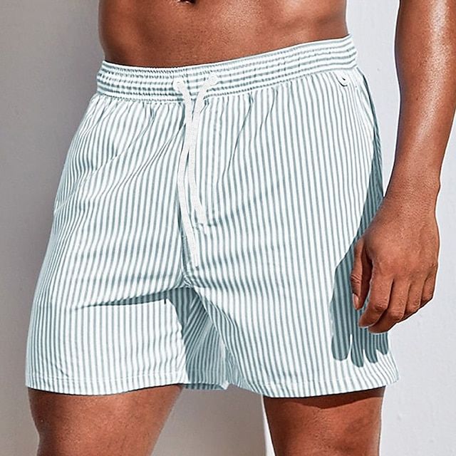 Man wearing quick-dry striped swim shorts on the beach. Ideal men's beachwear for versatile summer fashion.
