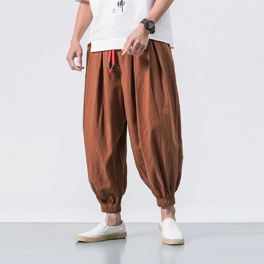 Man sitting comfortably in men's relaxed fit baggy harem jogger pants, ideal for lounging or active wear.