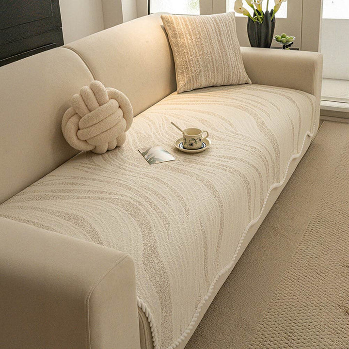 White ice silk couch cover with braided trim, covering a three-seater sofa, machine washable
