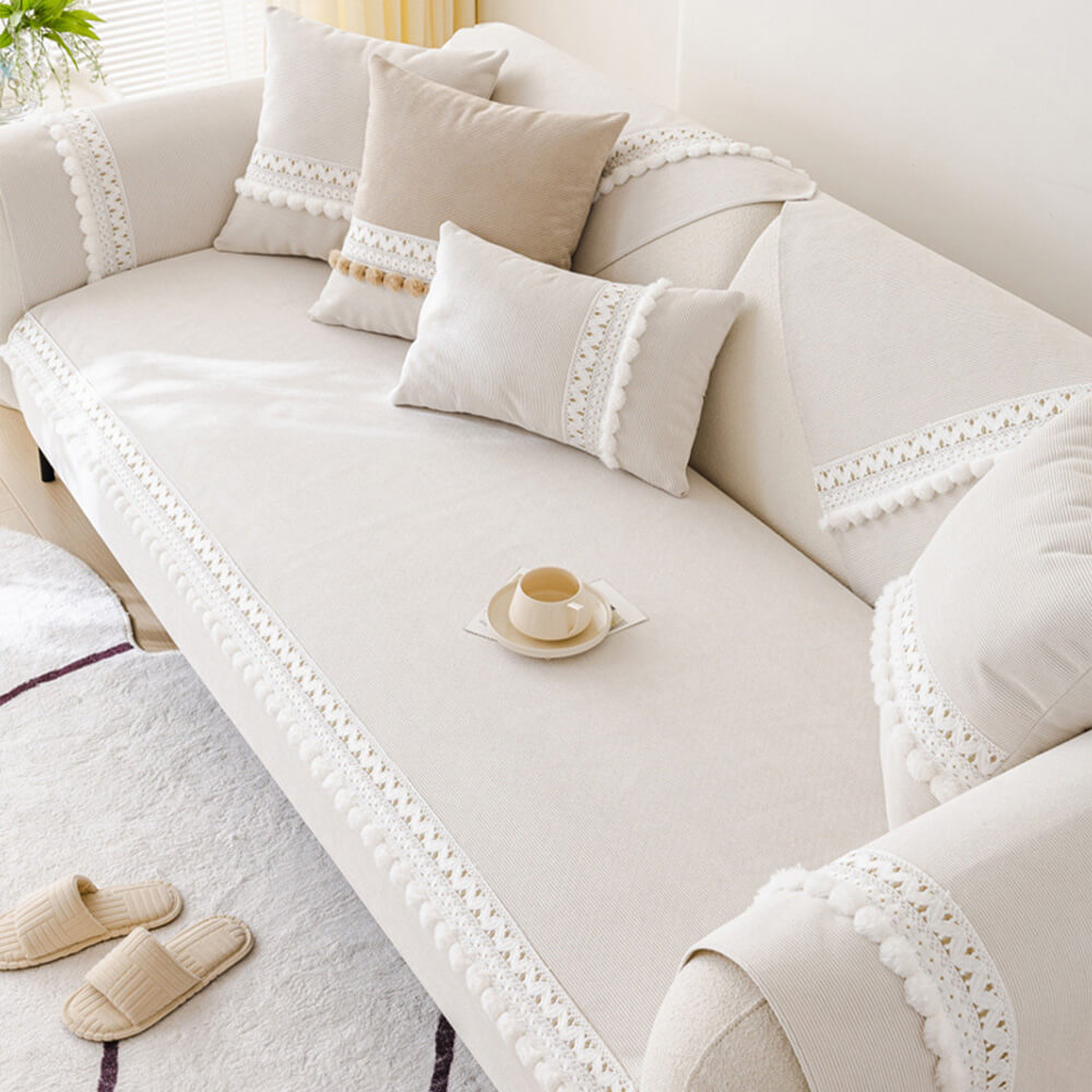 A child and pet friendly corduroy couch cover in a bright color with playful pom-poms.