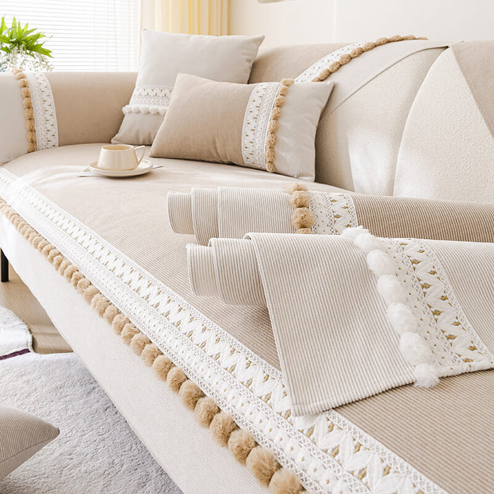 Display of a folded corduroy couch cover in navy, highlighting the soft texture and pom-pom trim.