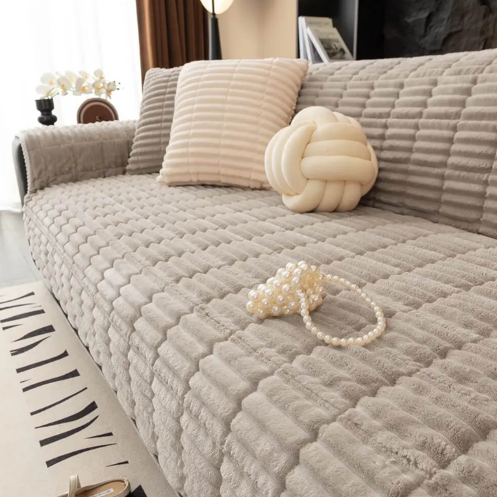 Non-slip flannel sofa cover in a neutral color, draped over a living room couch, spill resistant.
