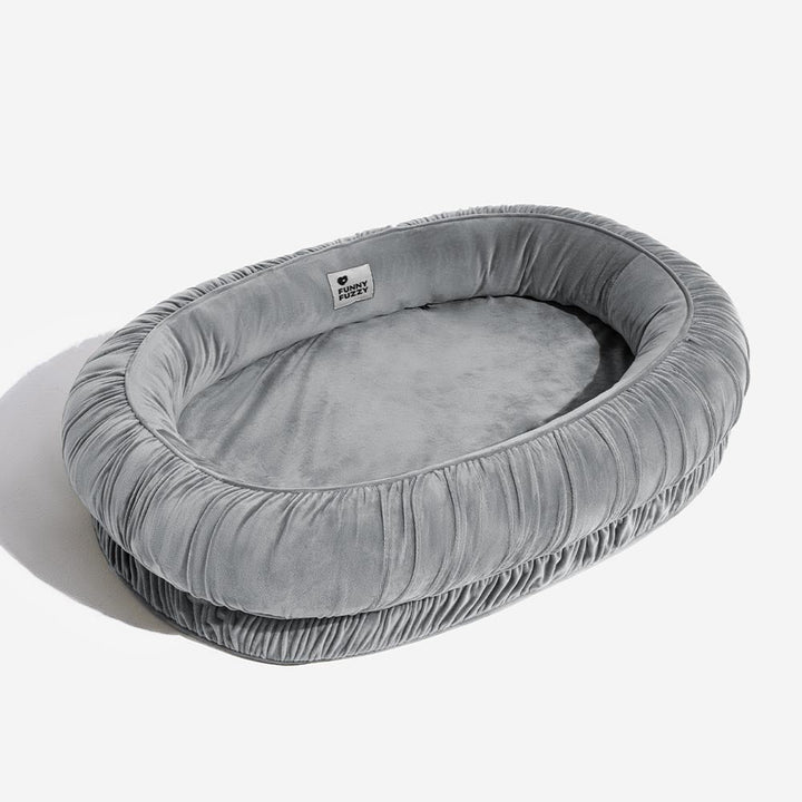 Velvet calming pet bed, orthopedic and oval shaped, providing warmth and comfort with a removable cover.