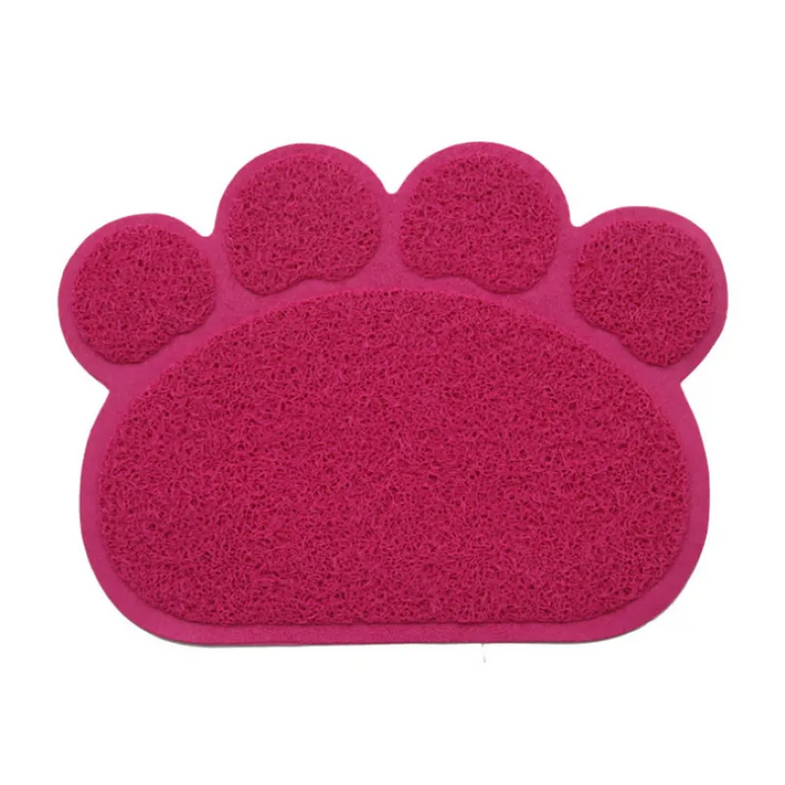 A cat stepping onto a grey paw-shaped litter mat, highlighting its use as a litter catcher.