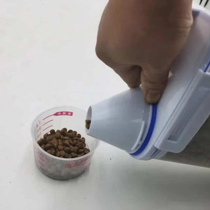 Durable plastic pet food dispenser with a clear design and marked measuring cup
