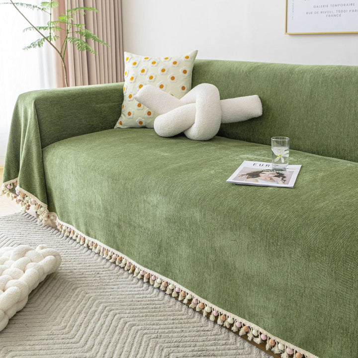 Pet friendly herringbone sofa cover with decorative tassels, protecting living room furniture from pets.