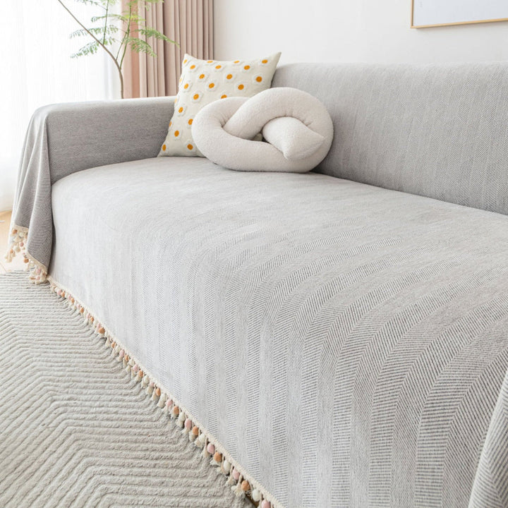 Close-up of herringbone texture on a pet friendly sofa cover with elegant tassel accents.