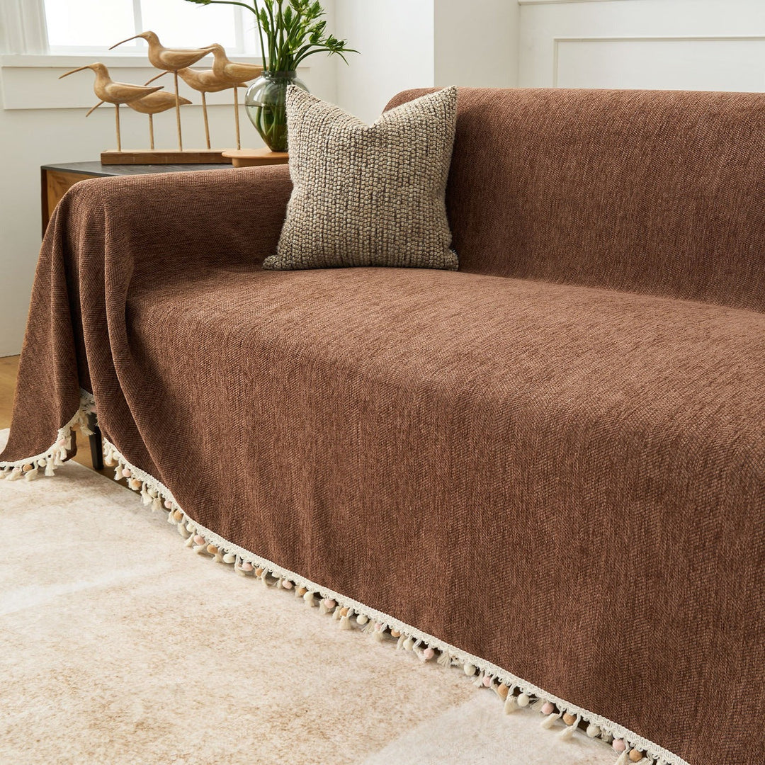 Detail of a tassel on a pet friendly herringbone sofa cover, enhancing boho living room decor.