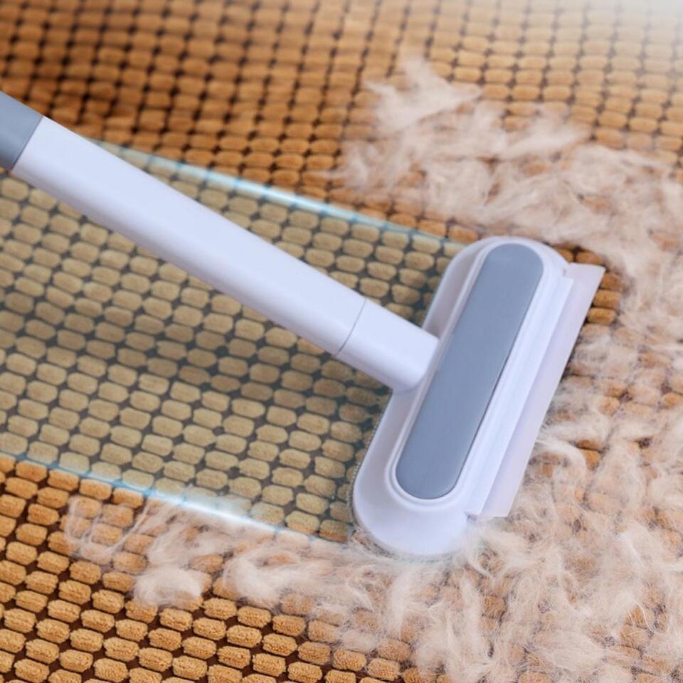 Hand using a reusable pet hair remover on a car seat, demonstrating easy fur and lint clean-up