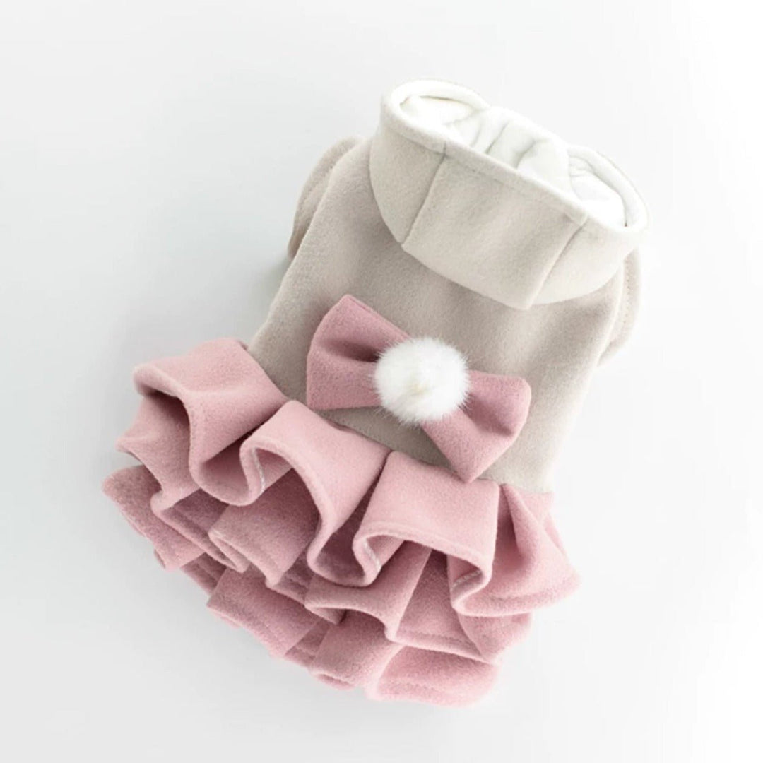 Small dog model showcasing a pink fleece dress jacket with a bow, trendy winter pet fashion