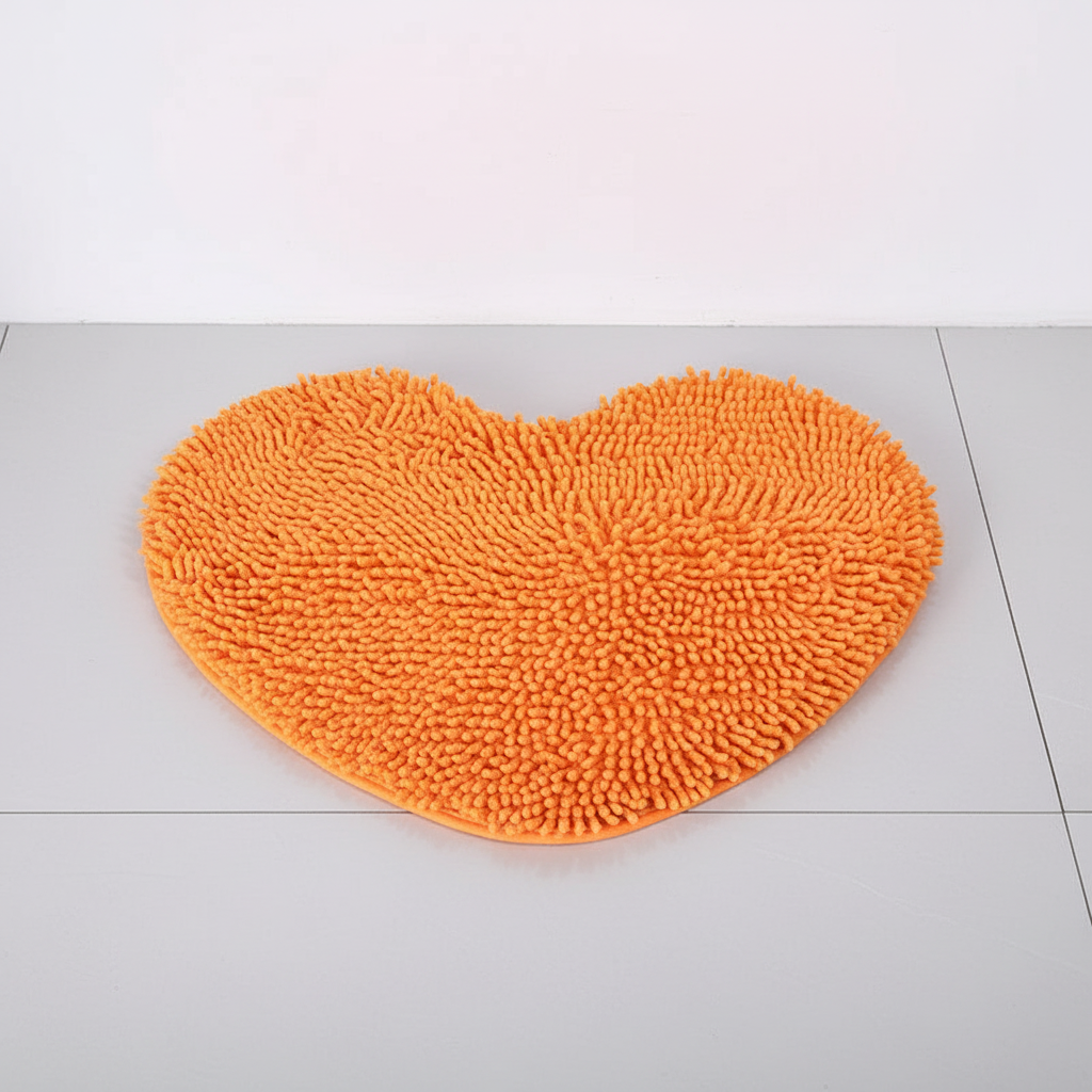 Vibrant orange heart-shaped plush bath mat. Absorbent microfiber & non-slip, perfect bathroom decor for home spa.