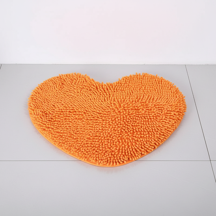 Vibrant orange heart-shaped plush bath mat. Absorbent microfiber & non-slip, perfect bathroom decor for home spa.