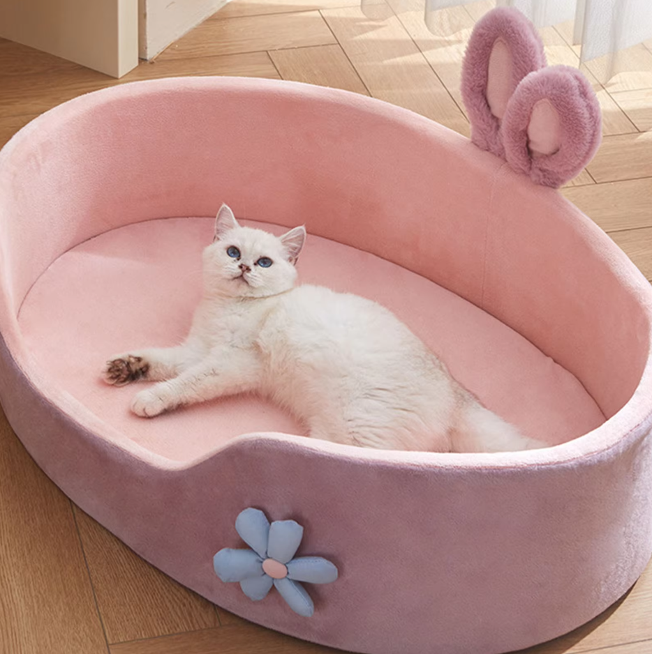 Soft pink cat bed designed with charming bunny ears and a delicate flower, providing a snug pet accessory.