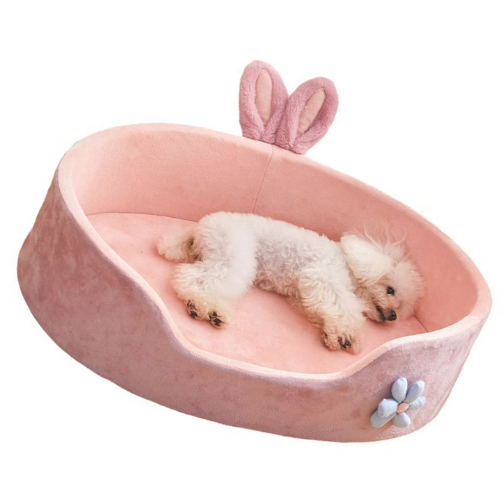 Comfortable pink pet bed with bunny ear accents and a flower, a soft and inviting spot for pets.