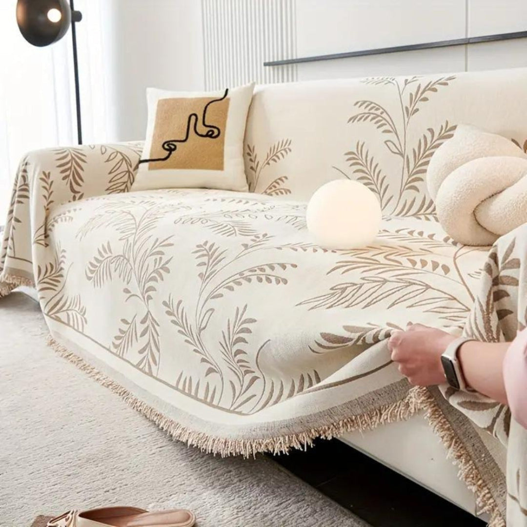 Plush chenille sofa couch cover in light grey with decorative tassels, draped on a living room sofa.