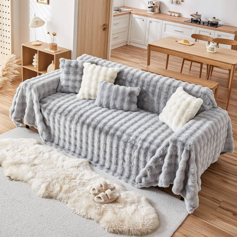 Unisex faux rabbit fur couch cover, designed for ultimate comfort and protection, draped over a three-seater sofa.