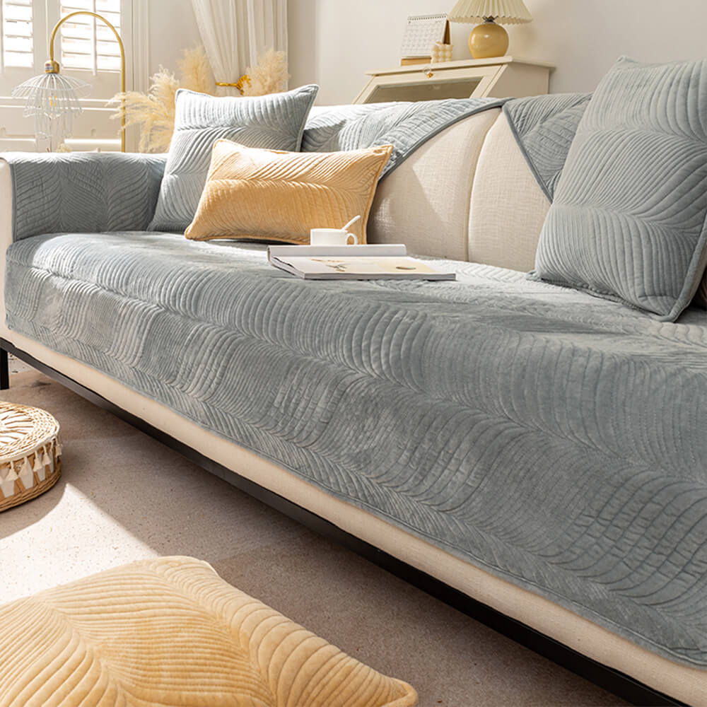 Plush non-slip sofa cover in a light color, displaying its leaf design for cozy home decor.