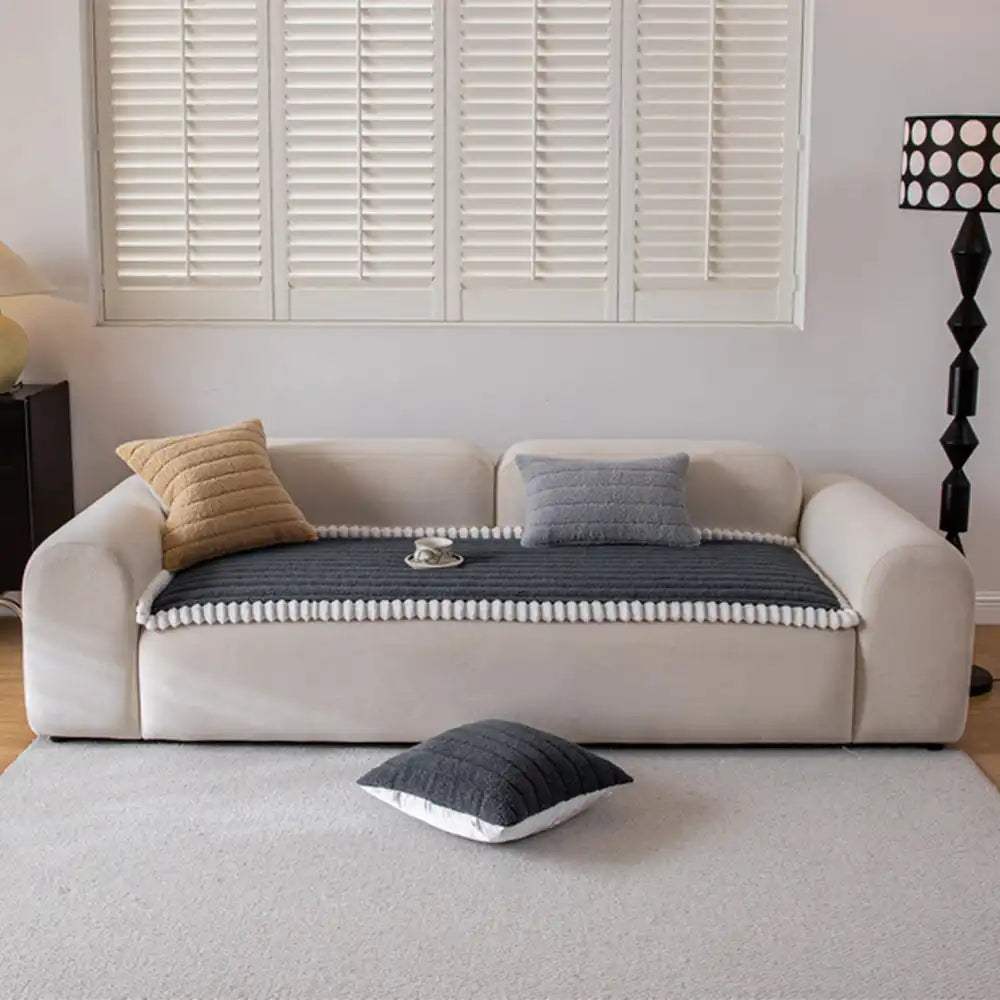 Packaging display of a universal non-slip machine washable sofa cover, highlighting features.