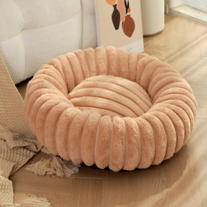 Grey plush donut pet bed on a hardwood floor, a modern and calming pet bed option.