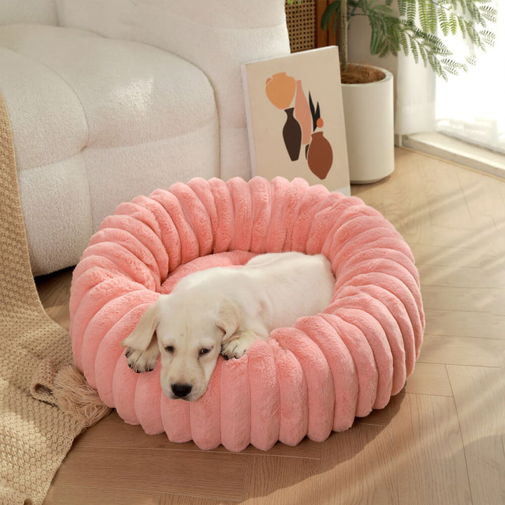 A small dog curled up contentedly in a plush donut pet bed, indicating comfort.