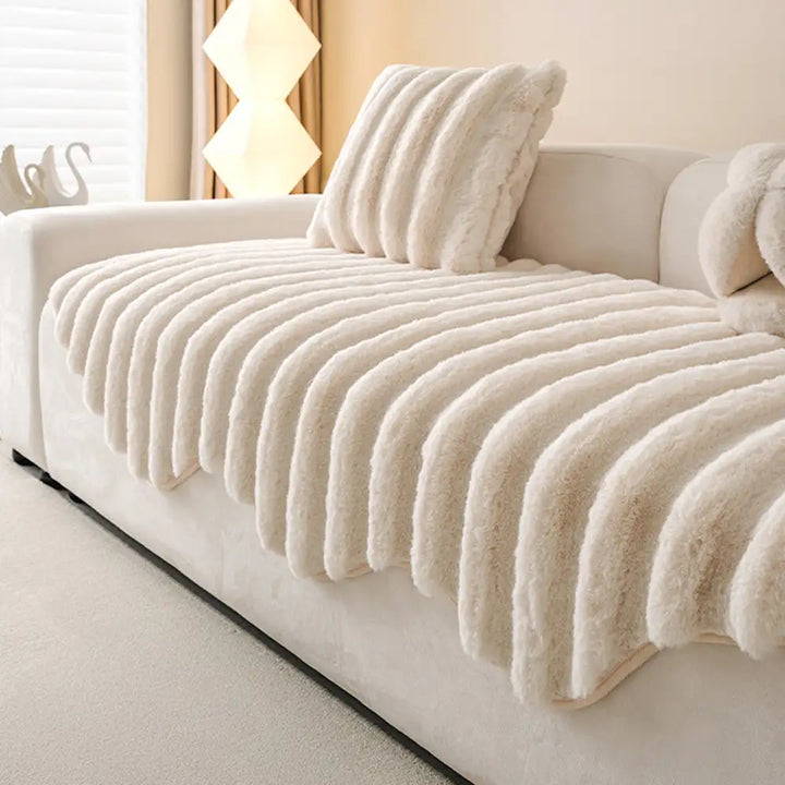 Sectional couch covered with a plush, non-slip furniture protector in a warm tone.