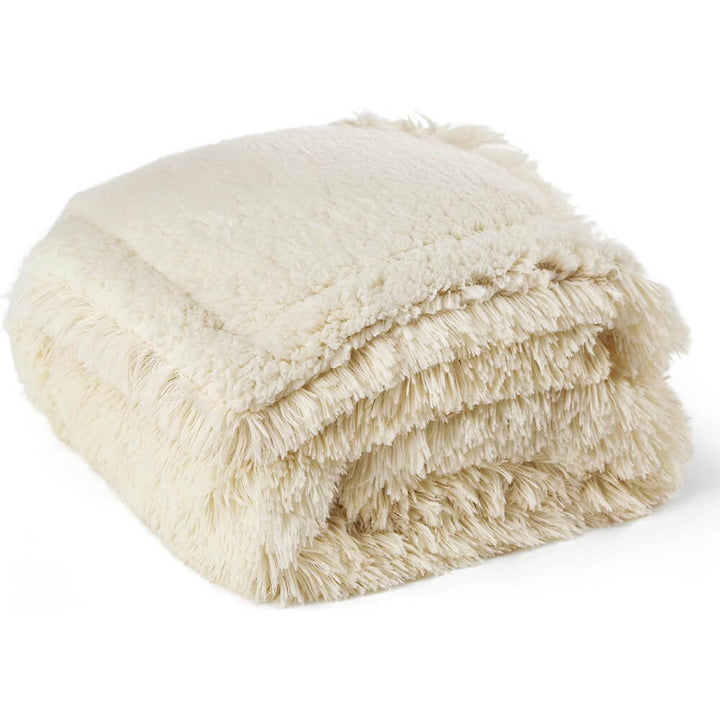 Puppy playfully tugging at a corner of a durable, waterproof plush pet throw blanket