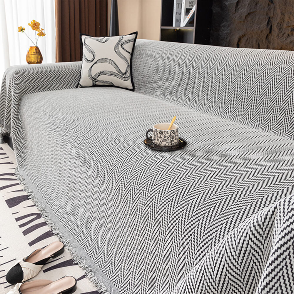 Luxurious herringbone chenille throw cover for sofa, featuring decorative fringe.