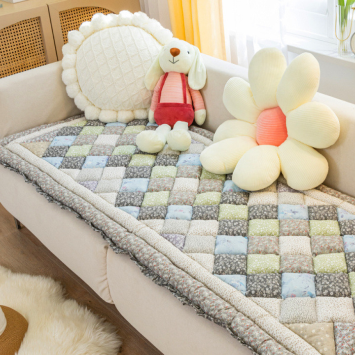 A corner view of a sofa with a new quilted floral non-slip couch cover, offering full coverage.