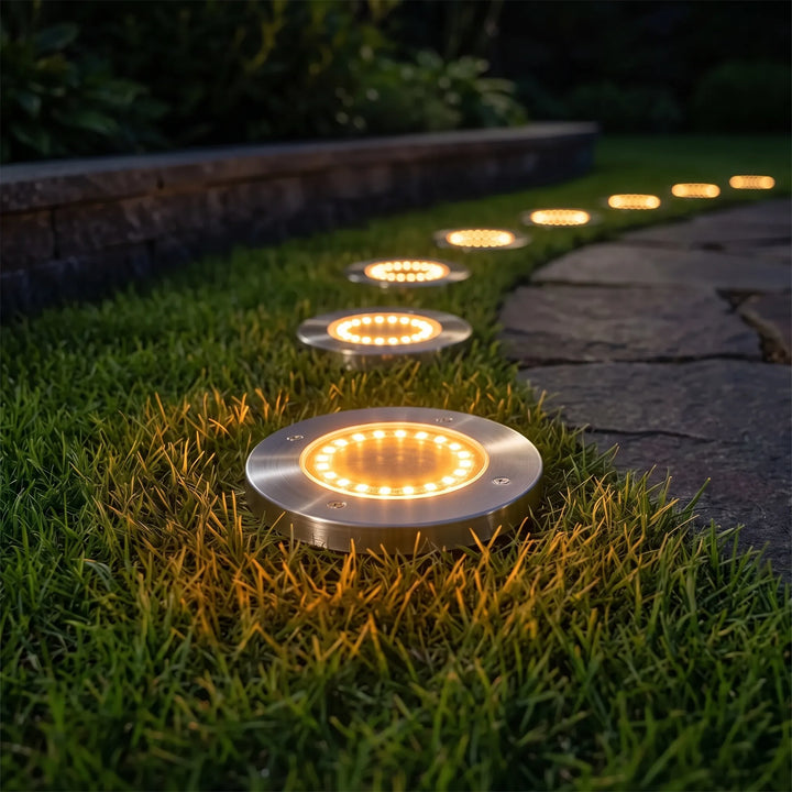 Warm white LED solar disk lights creating a soft glow along a garden pathway. Eco-friendly landscape lighting for patios.