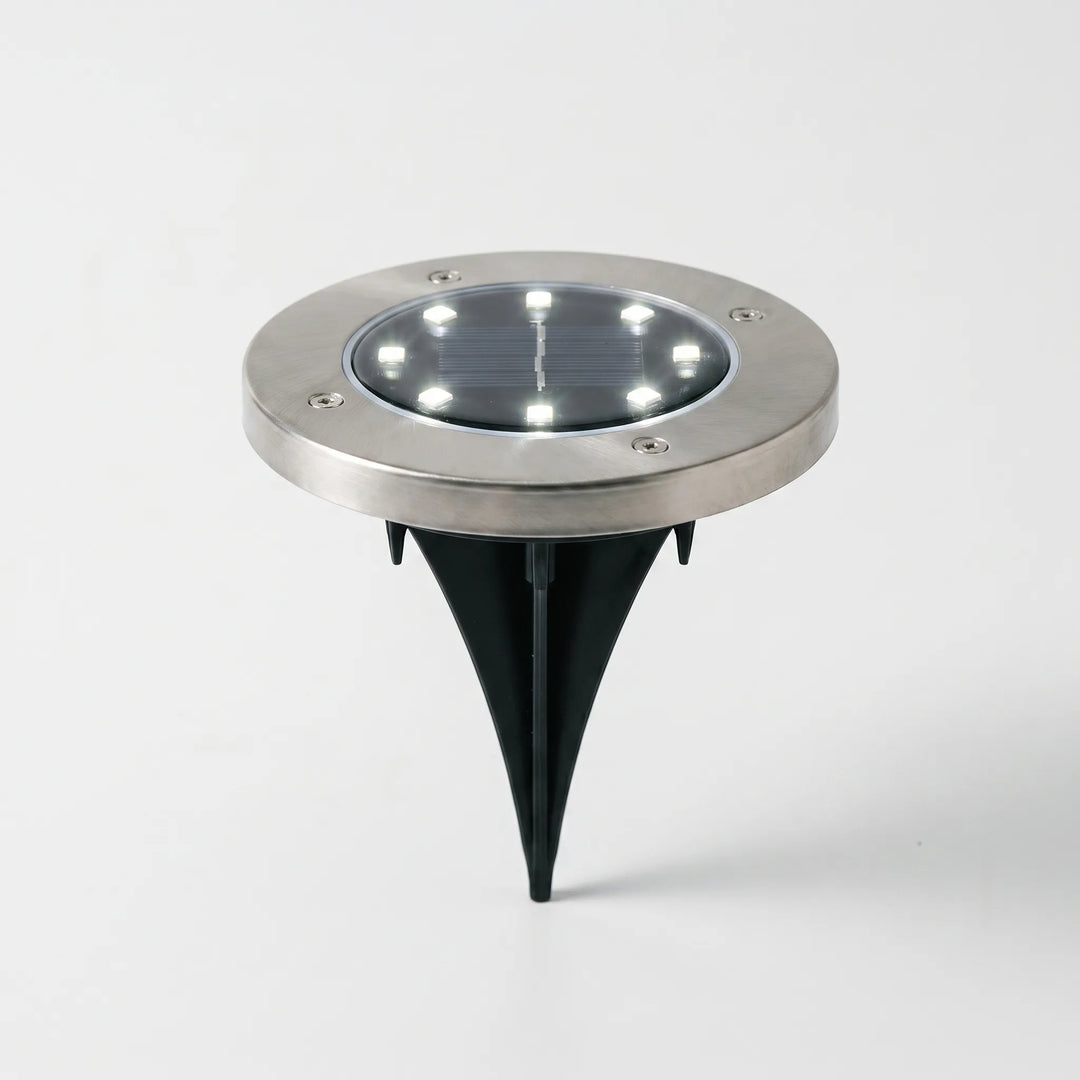 Close-up of a waterproof solar disk light, showcasing its bright LED for garden pathway illumination. Wireless design.