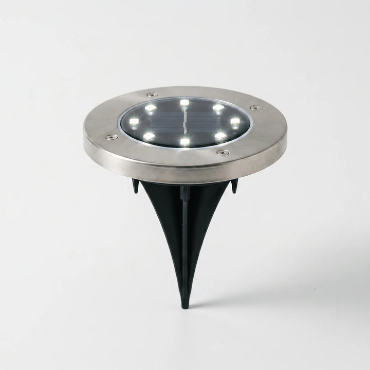 Close-up of a waterproof solar disk light, showcasing its bright LED for garden pathway illumination. Wireless design.