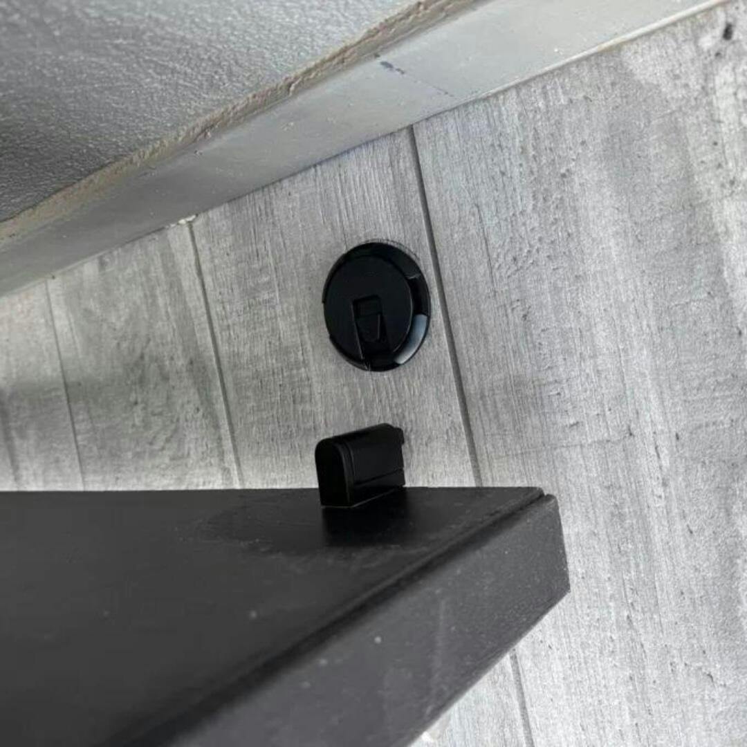 No-drill self-adhesive magnetic door stopper in black, prevents wall damage and holds doors securely.