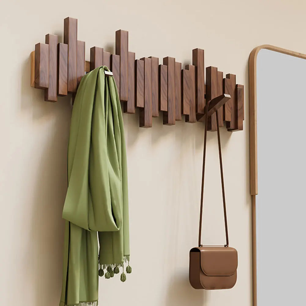 Modern natural wood wall-mounted coat rack with folding hooks for a clean, space-saving entryway.