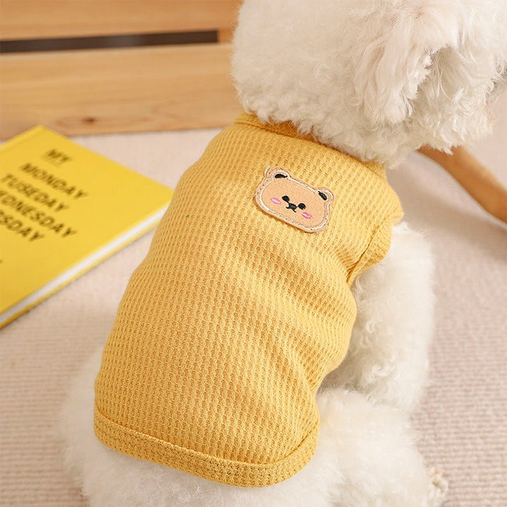 Small dog wearing a cozy beige waffle knit dog vest, perfect for autumn pet apparel.