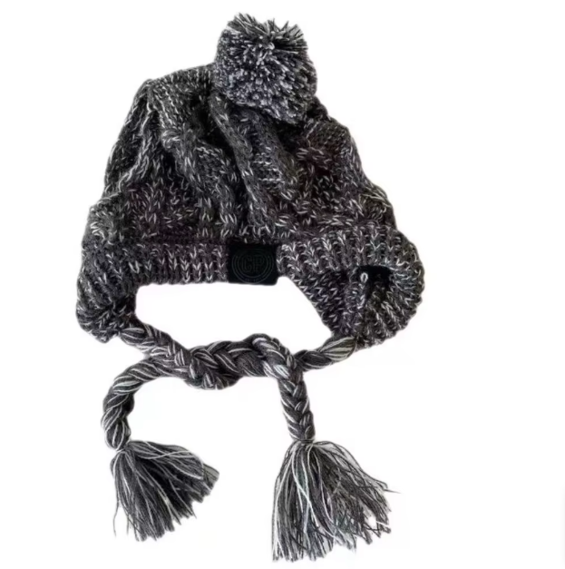 Warm pet clothing: an orange knitted dog hat with a fluffy pom-pom, close-up view.
