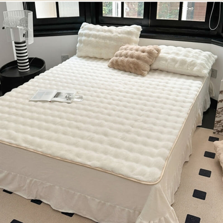 A person's hand touching the soft faux rabbit fur of a non-slip fitted mattress cover, bedding choice.