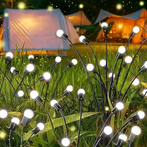 Solar firefly garden lights swaying gently in a dark outdoor garden, illuminating a starburst effect.