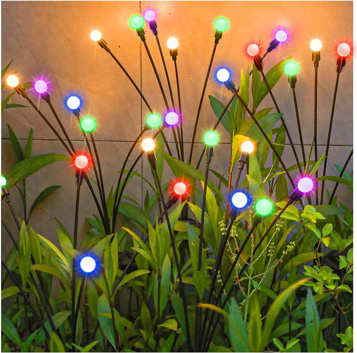 Night view of a garden with solar firefly lights glowing, enhancing the patio and lawn with starbursts.
