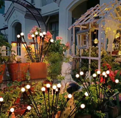 Waterproof solar firefly lights in a garden bed, adding a dynamic starburst lighting effect to lawn decor.