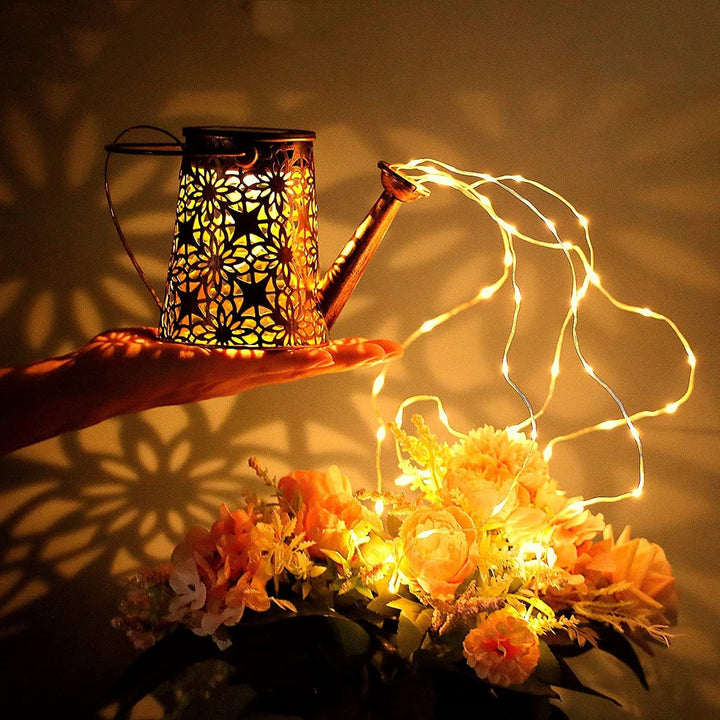 Elegant metal solar watering can with cascading fairy lights, enhances outdoor living areas.