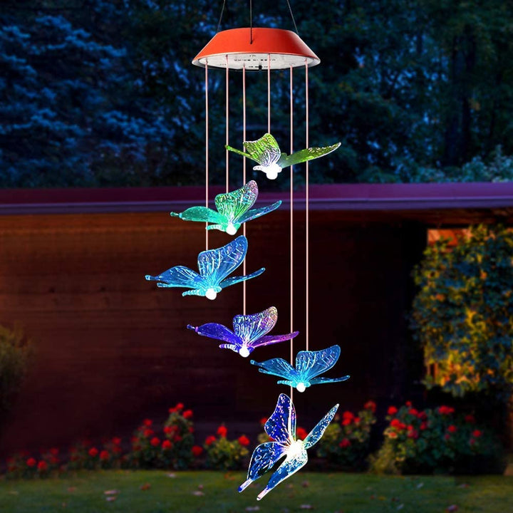 Solar-powered butterfly stake lights in a garden, glowing with changing colors at dusk.
